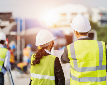 Businessman and businesswoman using see plan paper at construction site