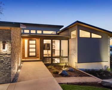 Beautiful modern style luxury home exterior at sunset with glowing interior lights.